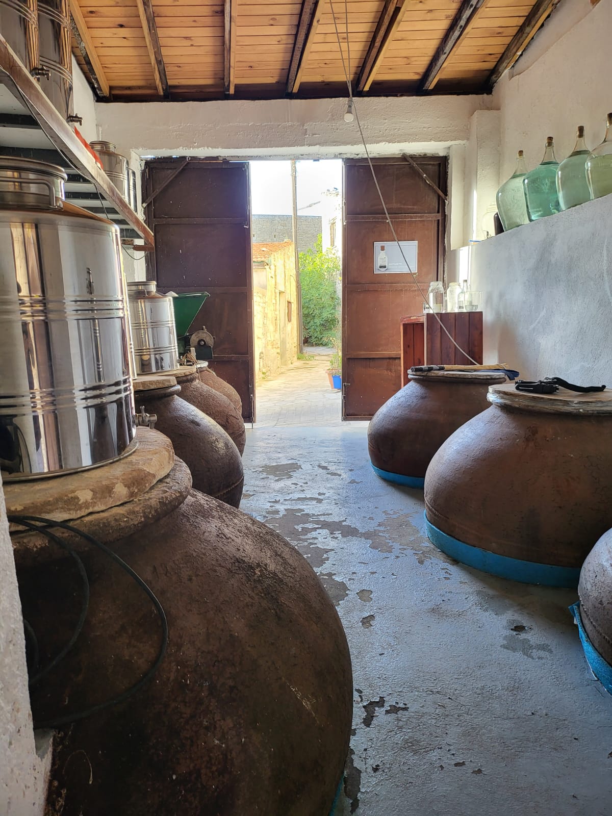 Clay pitharia lining the workshop floor with the village street beyond the open doors