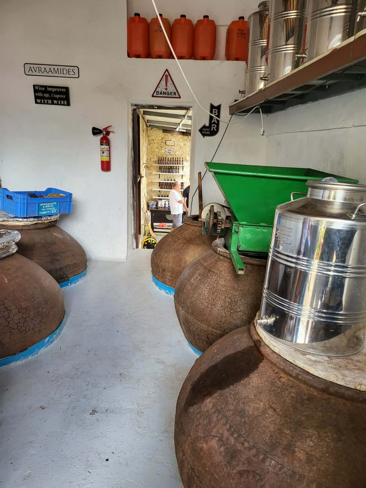 Row of terracotta pitharia beside the grape crusher inside the Avraamides workshop