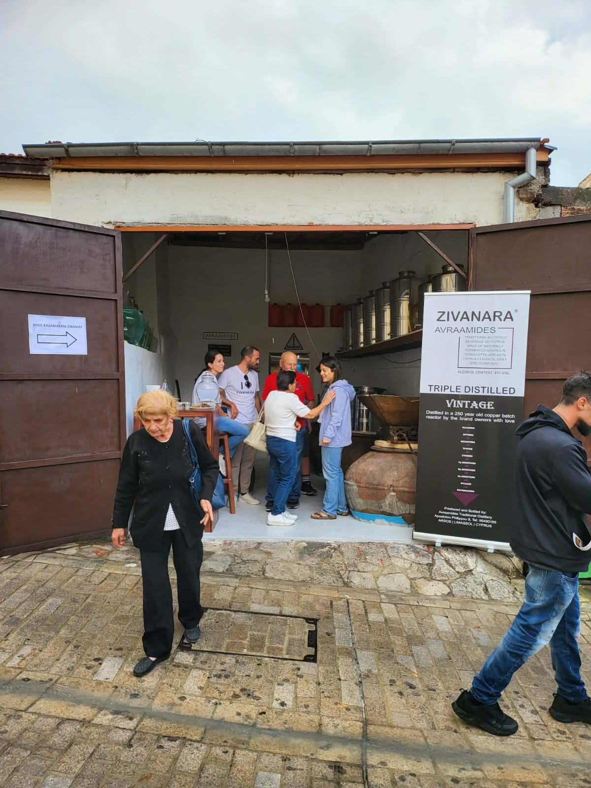 Visitors gathered at the Avraamides workshop entrance beside the Zivanara vintage banner